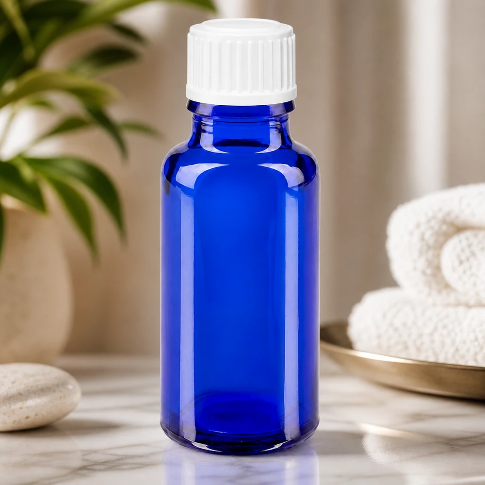Frasco de farmacia de cristal azul de 20 ml con tapón cuentagotas blanco sobre fondo de mármol