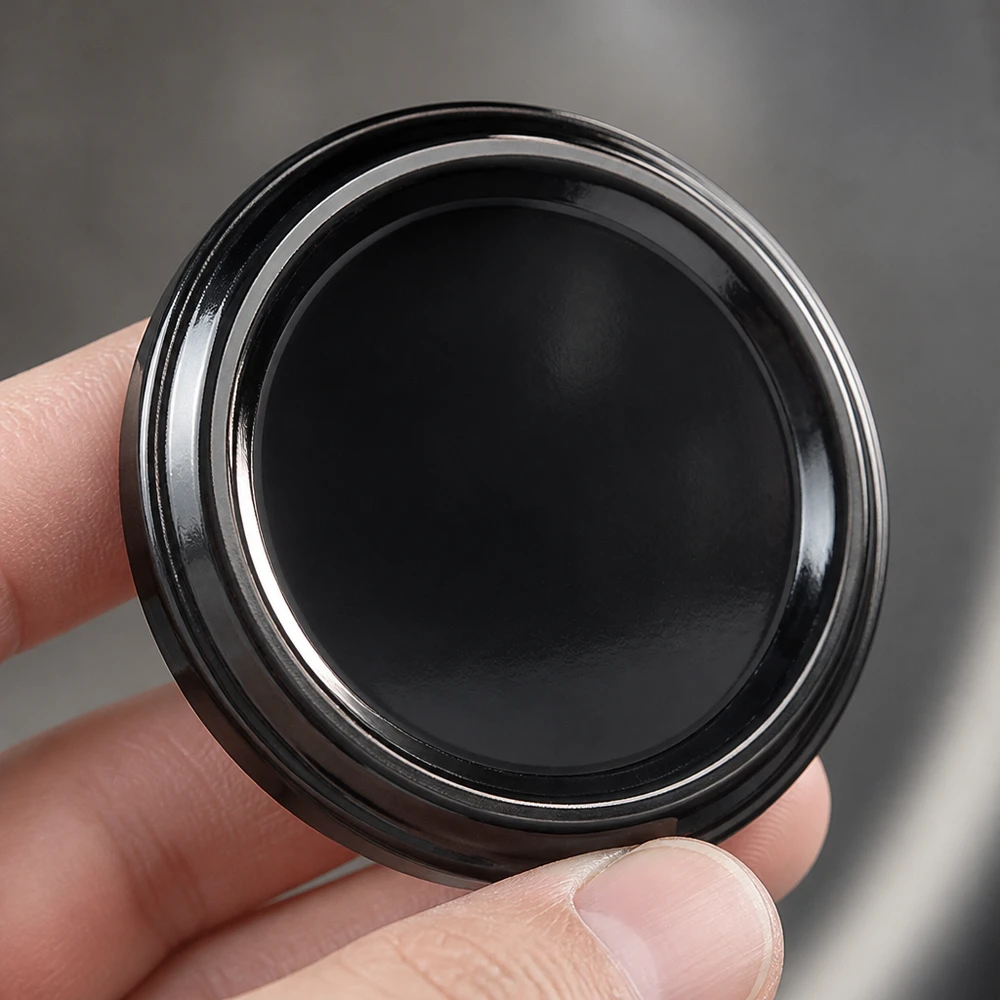 UNiTWIST TO48 negro, BioSeal, sin BPA, unitemp. UNiTWIST TO48 negro BioSeal sin BPA, primer plano de la superficie brillante de la tapa giratoria negra de 48 mm