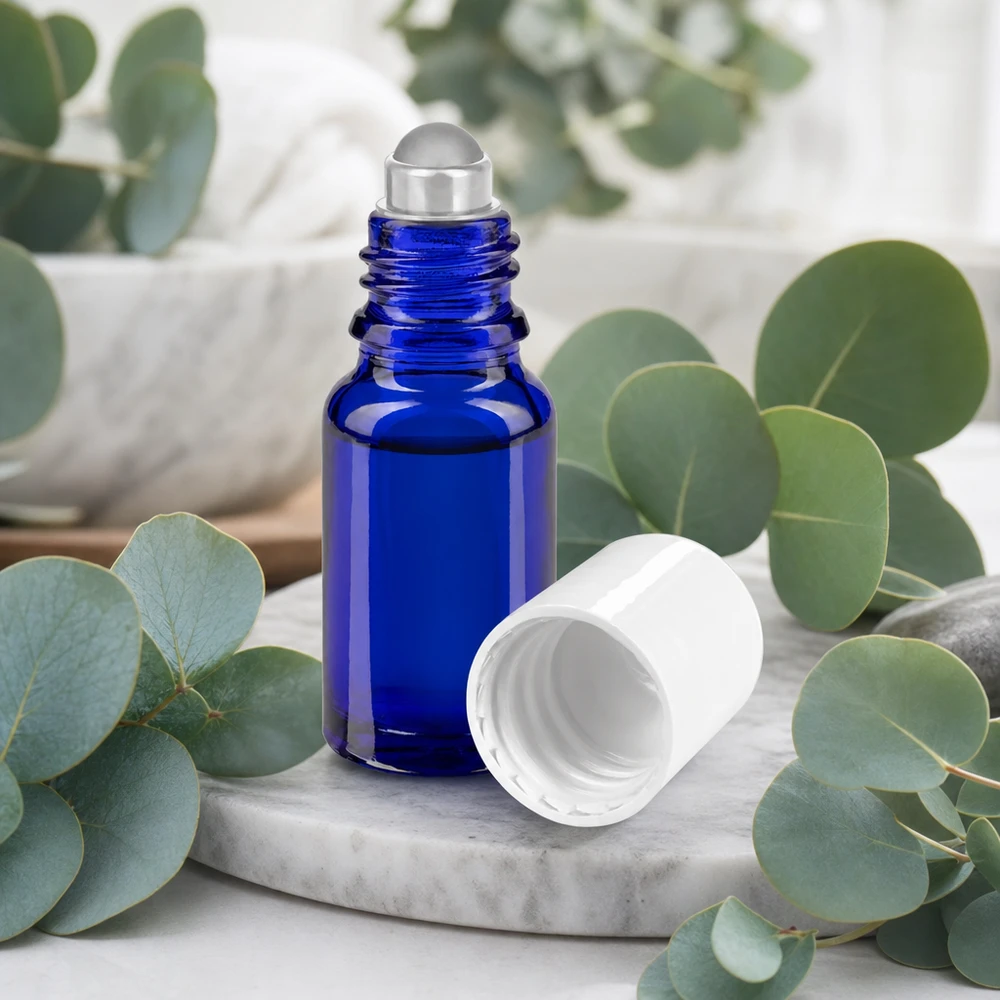 Frasco de cristal de farmacia de 10 ml de color azul cobalto con bola rodante de acero inoxidable y tapón blanco sobre fondo de mármol