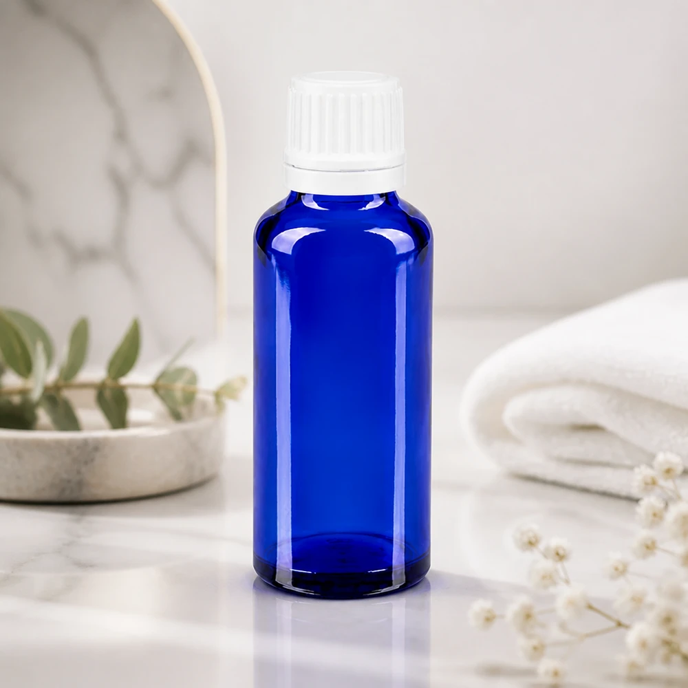 Botella de farmacia azul 30ml tapón cuentagotas 1.2mm blanco cierre inviolable Frasco de farmacia azul de 30 ml con dosificador de gotas de 0,7 mm sobre mármol blanco, junto a una toalla doblada