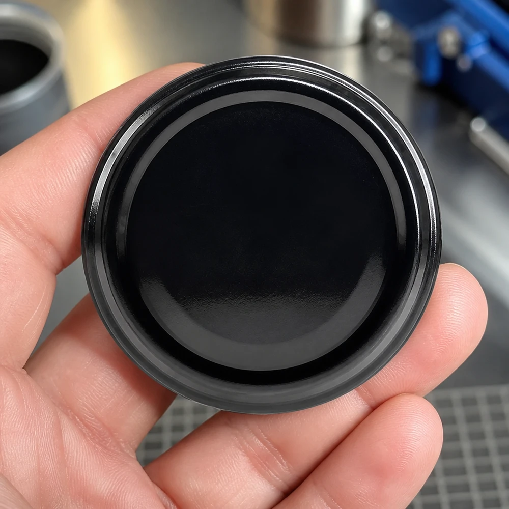 UNiTWIST TO48 negro, BioSeal, sin BPA, unitemp. Tapa de rosca UNiTWIST TO48 negra. Primer plano de la superficie brillante. BioSeal, sin BPA, unitemp, 48 mm