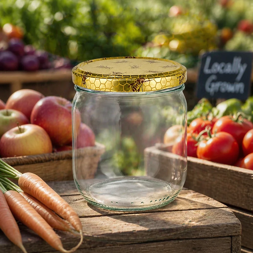 Tarro de miel de 500 g vacío con tapa de panal sobre una tabla de madera entre verduras frescas del mercado agrícola