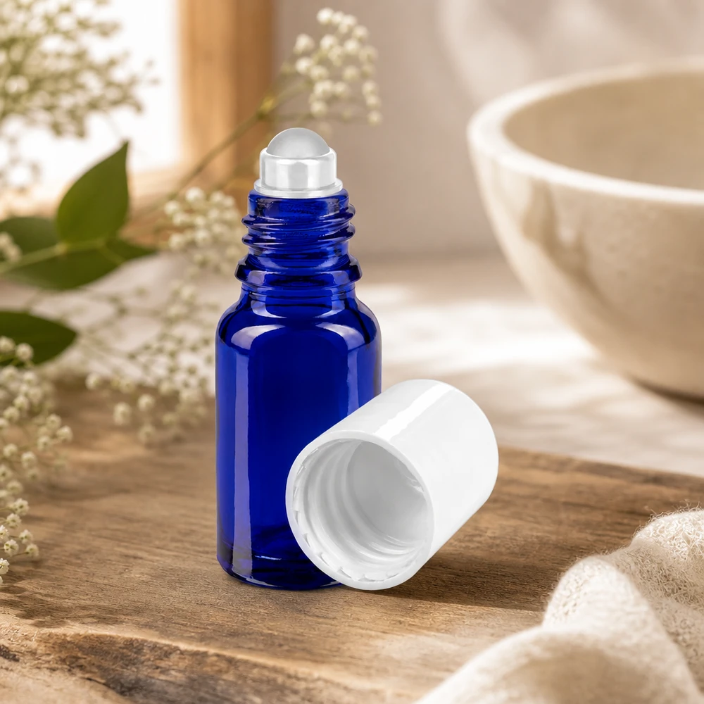 Frasco de cristal de 10 ml con aplicador de bola, de color azul cobalto, abierto y sin la tapa blanca, sobre un fondo de madera