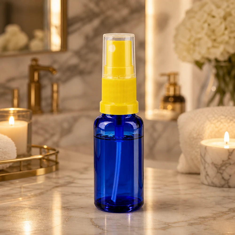 Botella de farmacia azul 20ml accesorio pulverizador amarillo Frasco atomizador de cristal azul de 20 ml con cabezal pulverizador amarillo sobre una repisa de mármol para el cuarto de baño