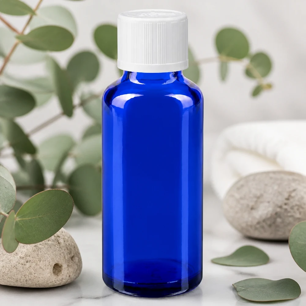 Botella de farmacia azul 30ml cuentagotas blanco estándar a prueba de niños Frasco de farmacia azul cobalto de 30 ml con tapón blanco KiSi sobre fondo de mármol, entre ramas de eucalipto