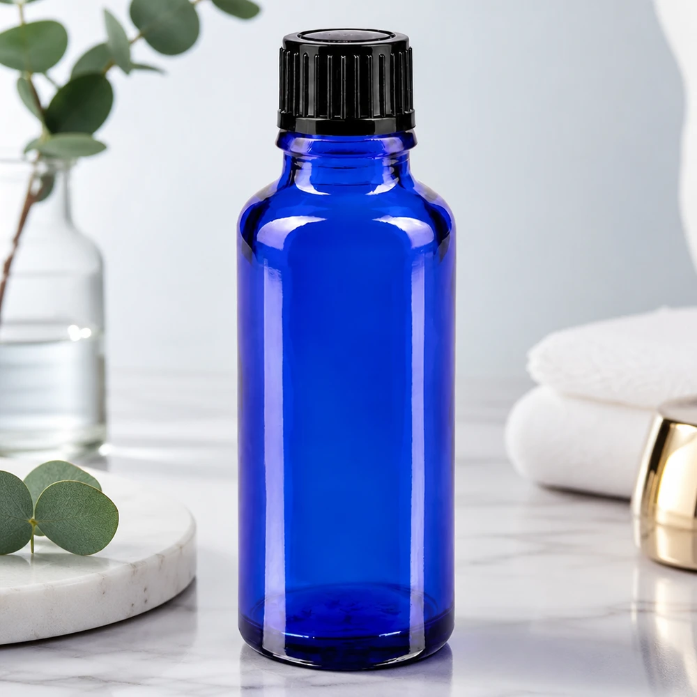 Frasco de cristal azul cobalto de 30 ml con tapón de rosca negro sobre una superficie de mármol blanco