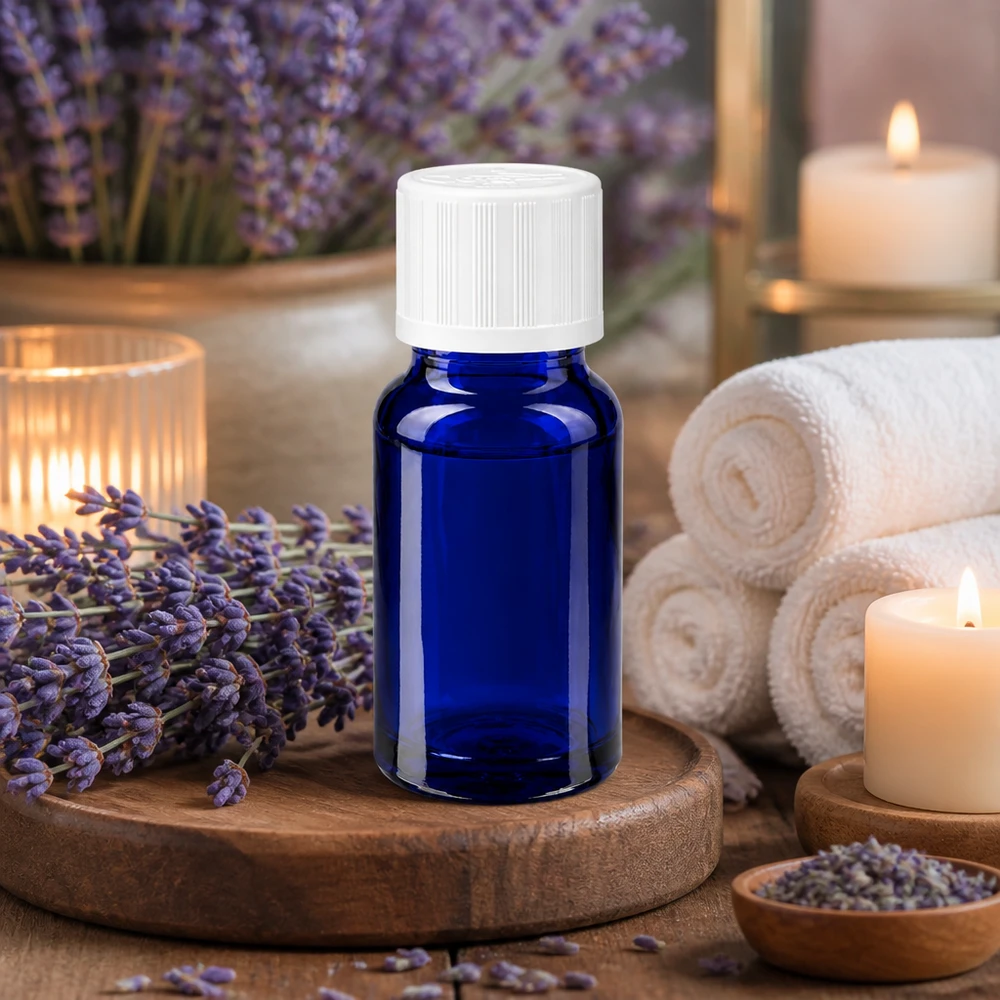 Frasco de cristal azul de 10 ml con tapón de seguridad para niños de color blanco, entre flores de lavanda y velas