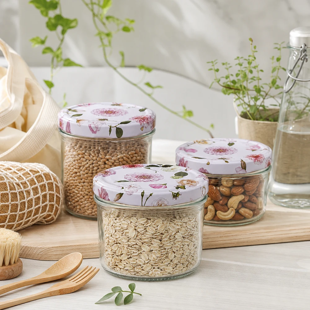 Tarro cilíndrico de 230 ml + tapa BasicSeal rosa flor Tres tarros cilíndricos de 230 ml con tapas de flores rosas rellenos de cereales y frutos secos en un entorno de cocina sostenible