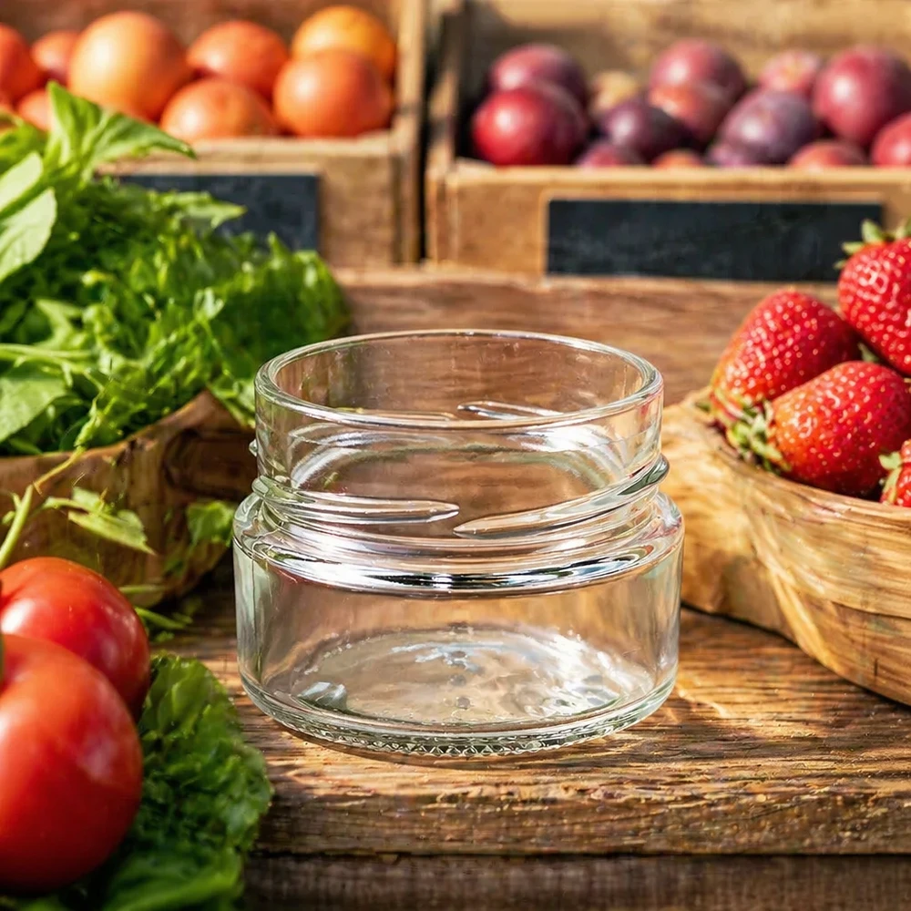 Tarro redondo de 80ml sin tapa (TO58deep) UNiTWIST UNiTWIST Runda80 tarro redondo 80ml TO58deep tarro de conserva vacío sobre mesa de madera con frutas y verduras frescas al fondo