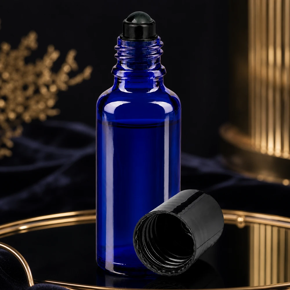 Frasco azul de 30 ml con aplicador de bola, con la tapa de rosca negra abierta, sobre una bandeja dorada