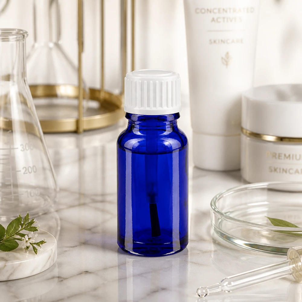 Botella de farmacia azul 10ml tapón rosca cepillo blanco Pequeña botella de cristal azul de 10 ml con tapón de rosca blanco sobre mármol, entre material de laboratorio