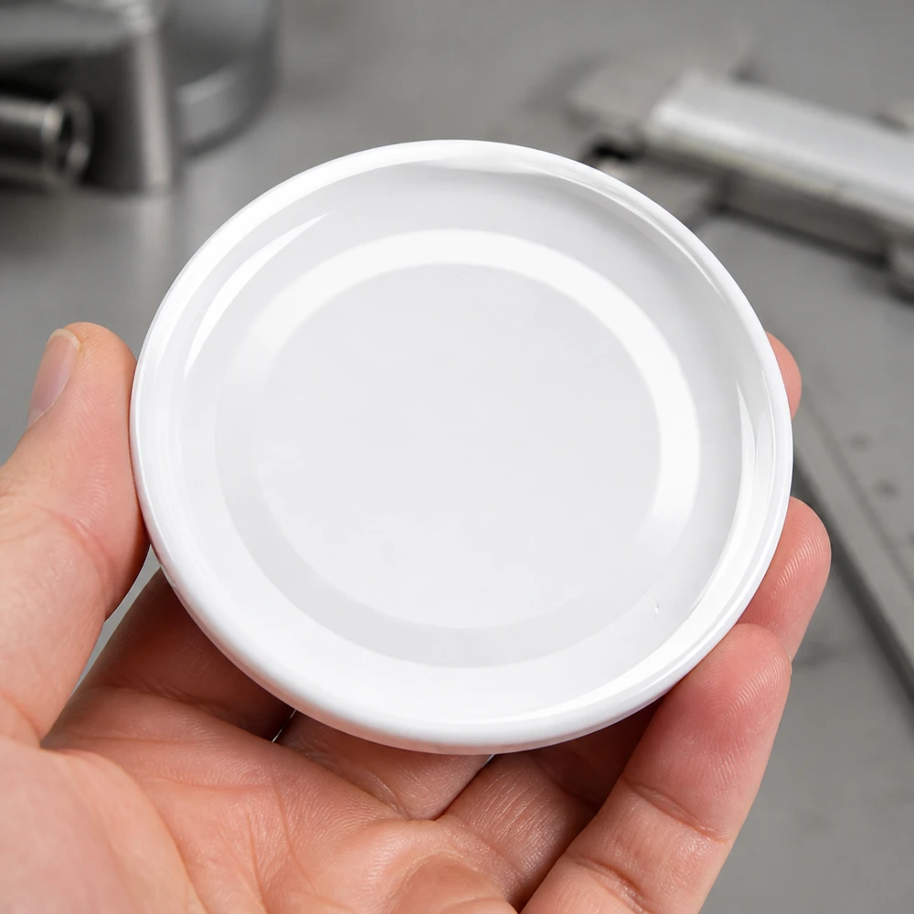 Tapa BasicSeal de 43 mm, blanca (TO43) UNiTWIST Primer plano de una tapa blanca TO43 de 43 mm, modelo BasicSeal UniTwist, de forma redonda, sobre la palma de la mano