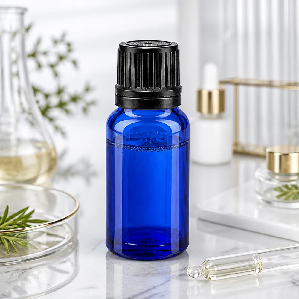 Frasco cuentagotas azul de 10 ml, fabricado en vidrio con protección UV y con tapón de seguridad negro, sobre fondo de mármol
