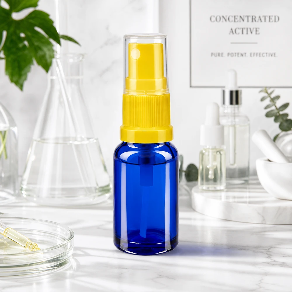 Frasco azul de 10 ml con mecanismo pulverizador amarillo y tapón protector sobre una superficie de mármol blanco