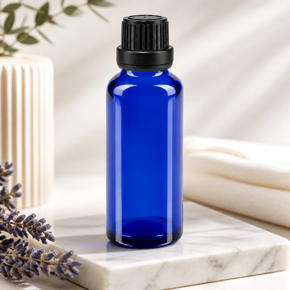 Frasco cuentagotas ApoGlas azul de 30 ml con boquilla de 2 mm y tapón negro, junto a una lavanda sobre mármol