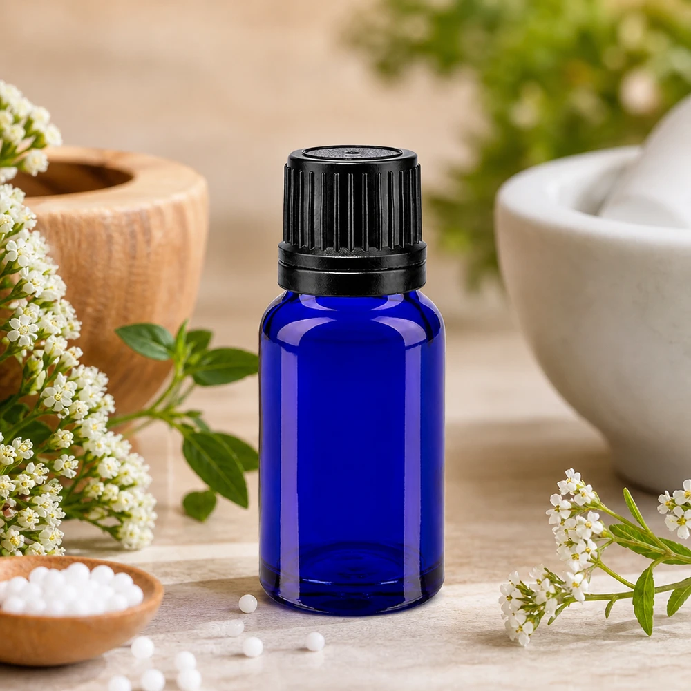 Frasco de farmacia azul de 10 ml con tapón OV negro, entre flores blancas y un mortero