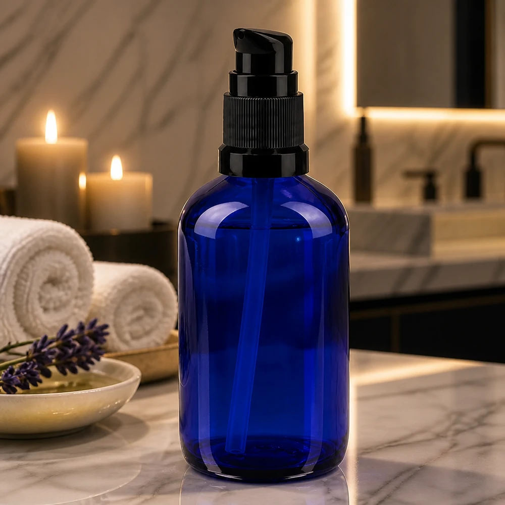 Botella de farmacia azul 100ml tapón bomba negro estándar Elegante frasco con dosificador de 100 ml, de cristal azul de farmacia, con un dosificador negro sobre una superficie de mármol, junto a unas velas