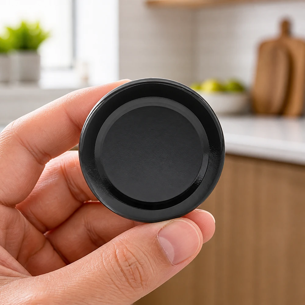 Tapa BasicSeal de 66 mm, negra (TO66deep) UNiTWIST Tapa negra de rosca «Twist-Off» BasicSeal TO66deep de 66 mm, sostenida con una mano en la cocina