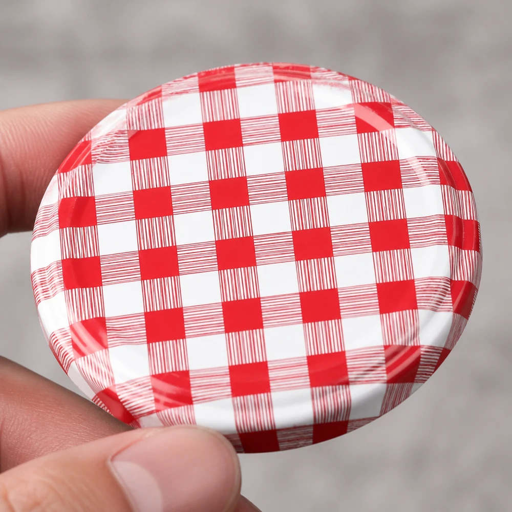 Tapa BasicSeal de 82 mm, a cuadros rojos y blancos (TO82) UNiTWIST Primer plano de la tapa metálica TO82 de 82 mm con el diseño clásico a cuadros rojos y blancos de BasicSeal