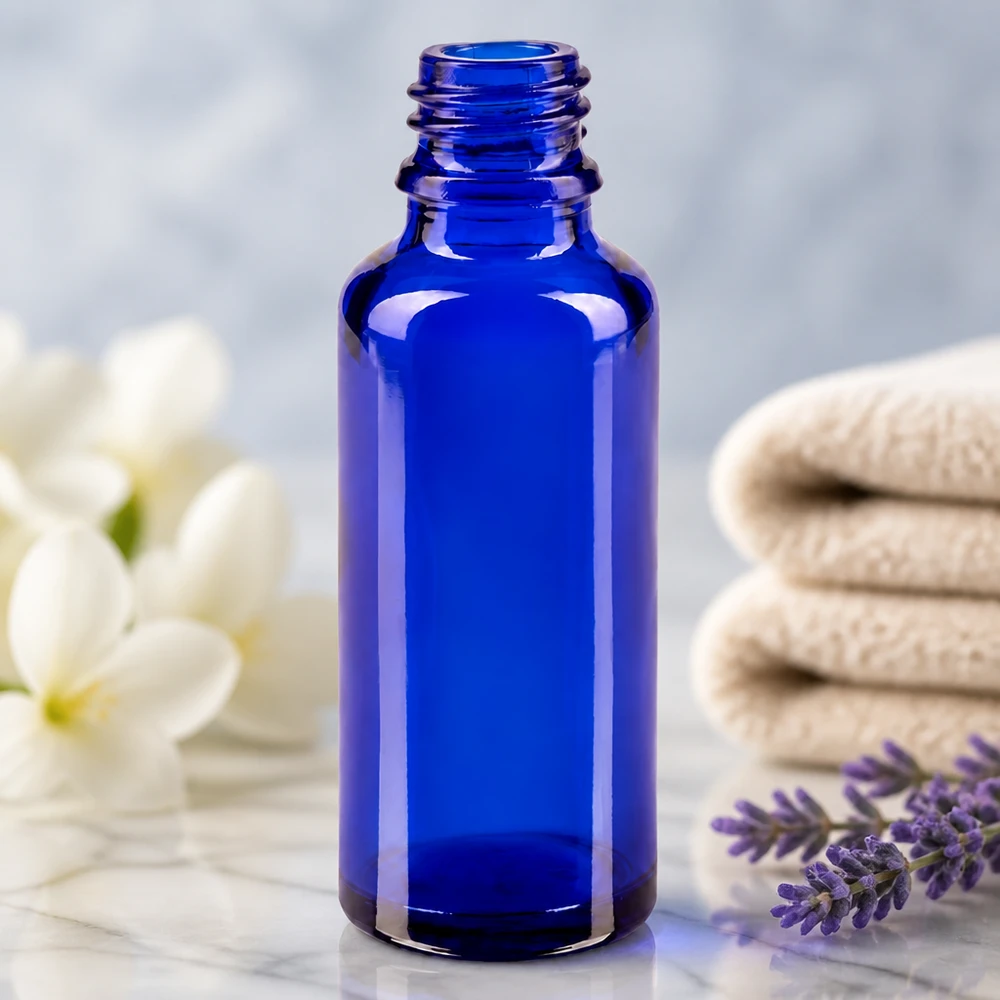 Frasco de farmacia ApoGlas vacío de 30 ml en azul real junto a una ramita de lavanda y flores blancas