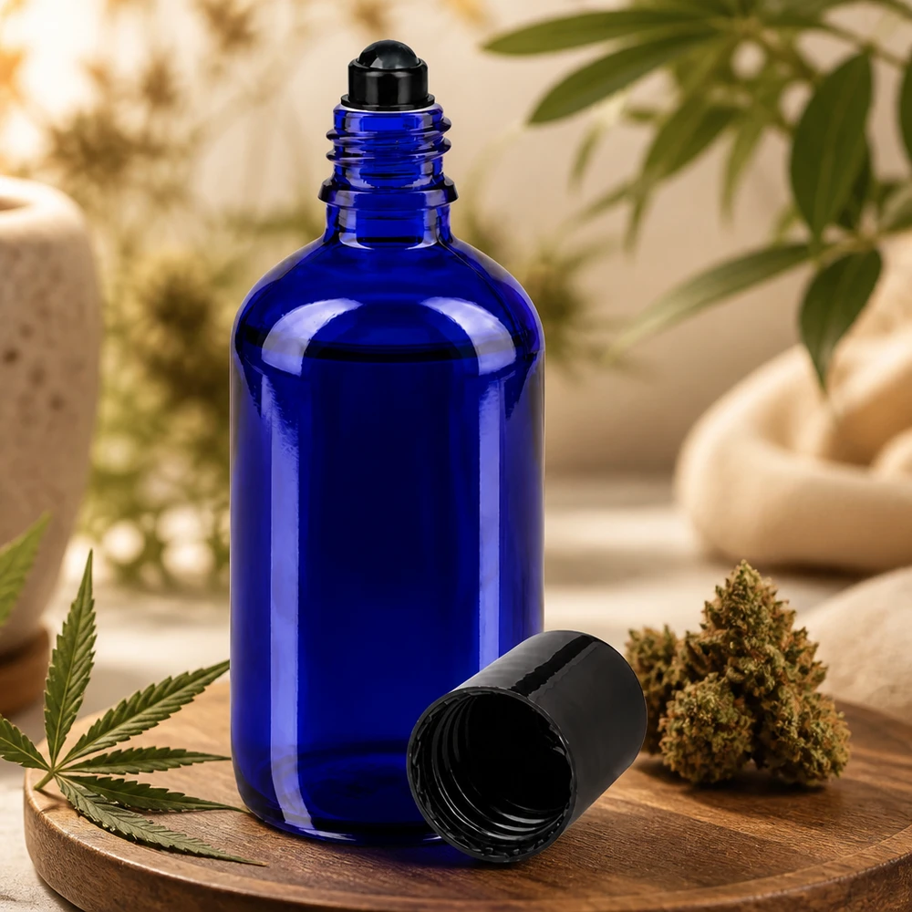 Frasco azul de 100 ml con aplicador de bola, de cristal de farmacia, junto a una flor de cannabis y una hoja de cáñamo sobre una tabla de madera