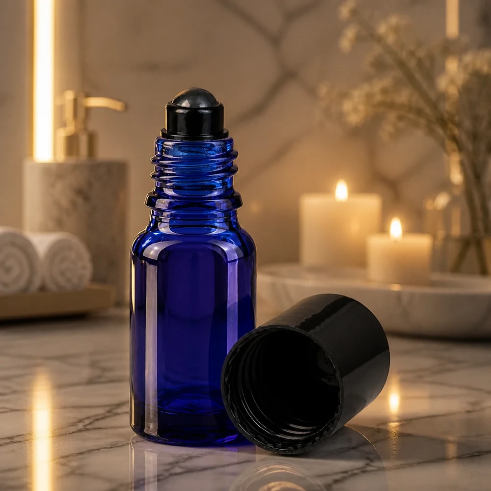 Botella de farmacia azul 10ml tapón roll-on negro Frasco roll-on azul cobalto de 10 ml con bola rodante negra, bajo la evocadora luz de las velas sobre mármol