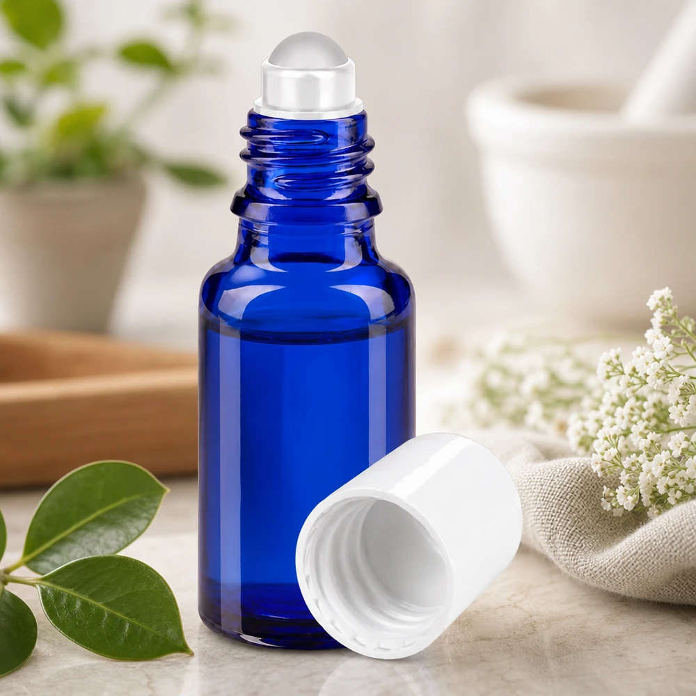 Frasco de farmacia azul de 20 ml con una bola rodante transparente junto a flores blancas y hojas verdes