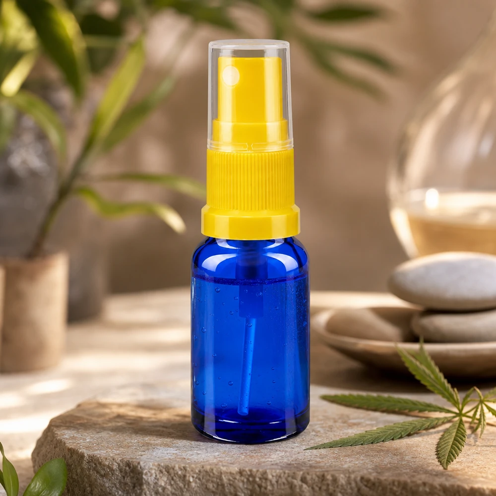 Mini frasco cuentagotas azul de 10 ml con mecanismo pulverizador amarillo transparente sobre piedra natural con una hoja de cannabis