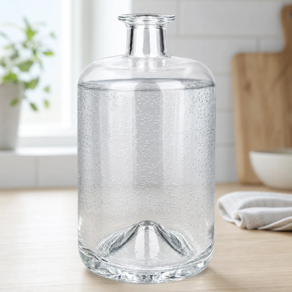 Botella de farmacia de 700 ml «Sofia» sin tapón UNiTWIST® La botella de cristal Sofía de 700 ml llena de agua con gas muestra burbujas de dióxido de carbono en un ambiente de cocina luminoso