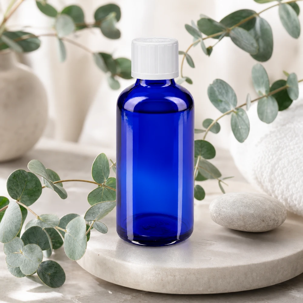 Frasco de farmacia azul de 50 ml con tapón de seguridad blanco sobre una bandeja de mármol con aroma a eucalipto