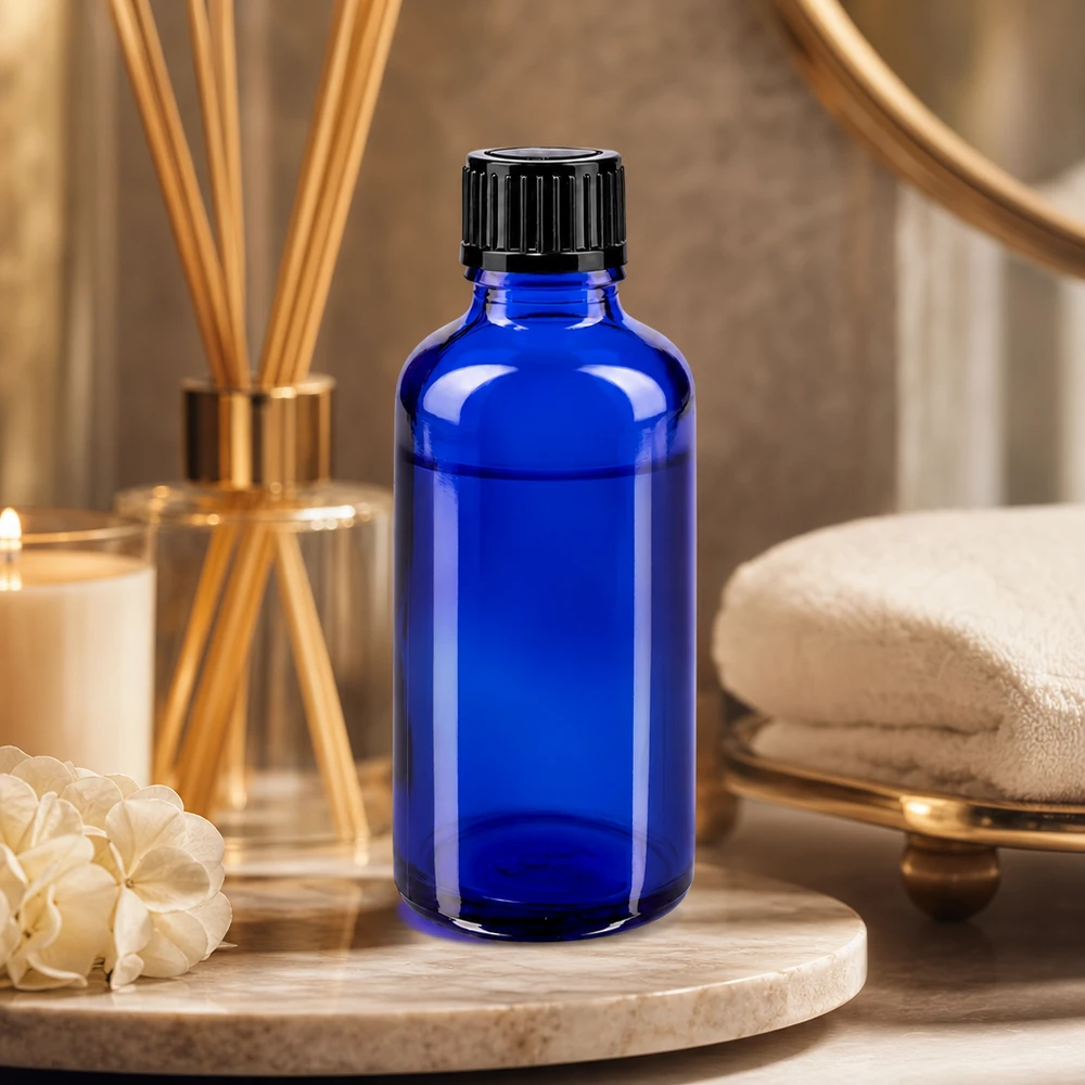 Frasco cuentagotas de 50 ml de color azul cobalto, de cristal de farmacia, con tapón de rosca negro, en un ambiente de spa
