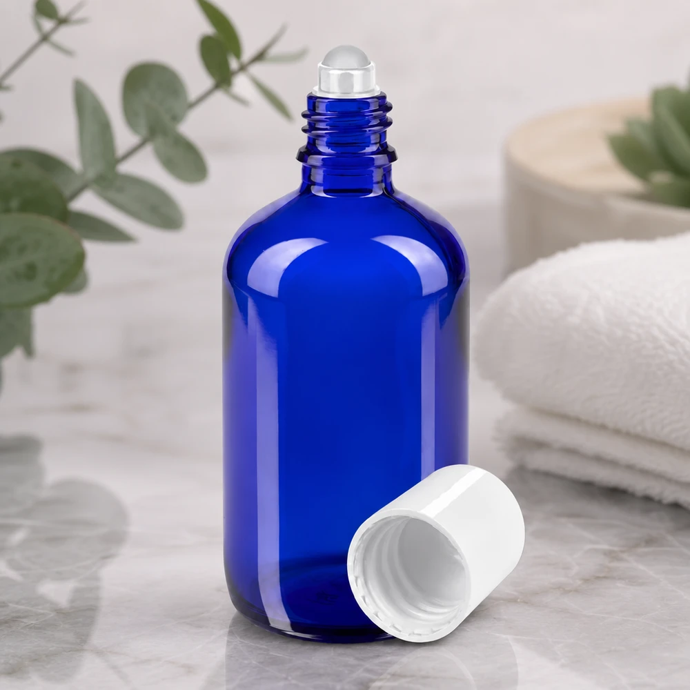 Frasco roll-on abierto de 100 ml en color azul cobalto, con una bola de cristal transparente y una tapa de plástico blanco