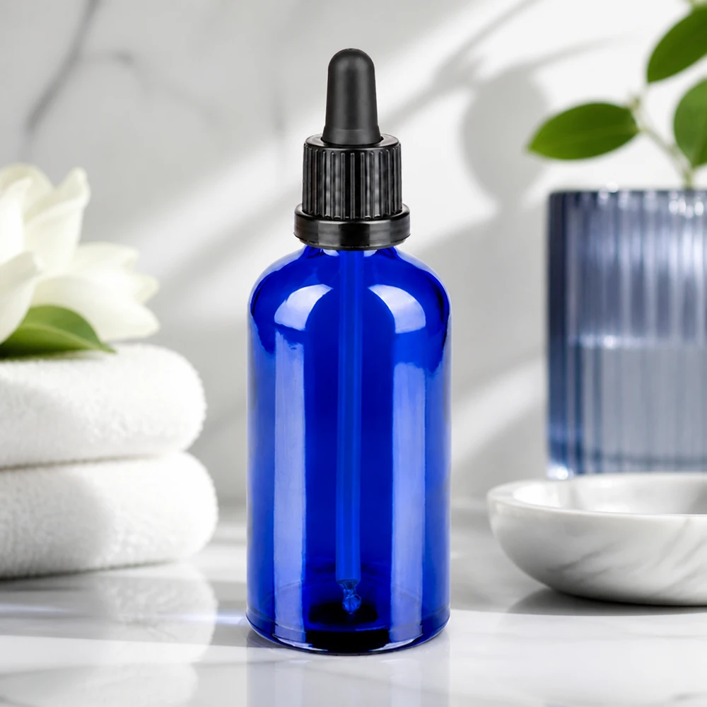 Elegante botella de cristal azul de 100 ml con pipeta negra para una presentación elegante del producto