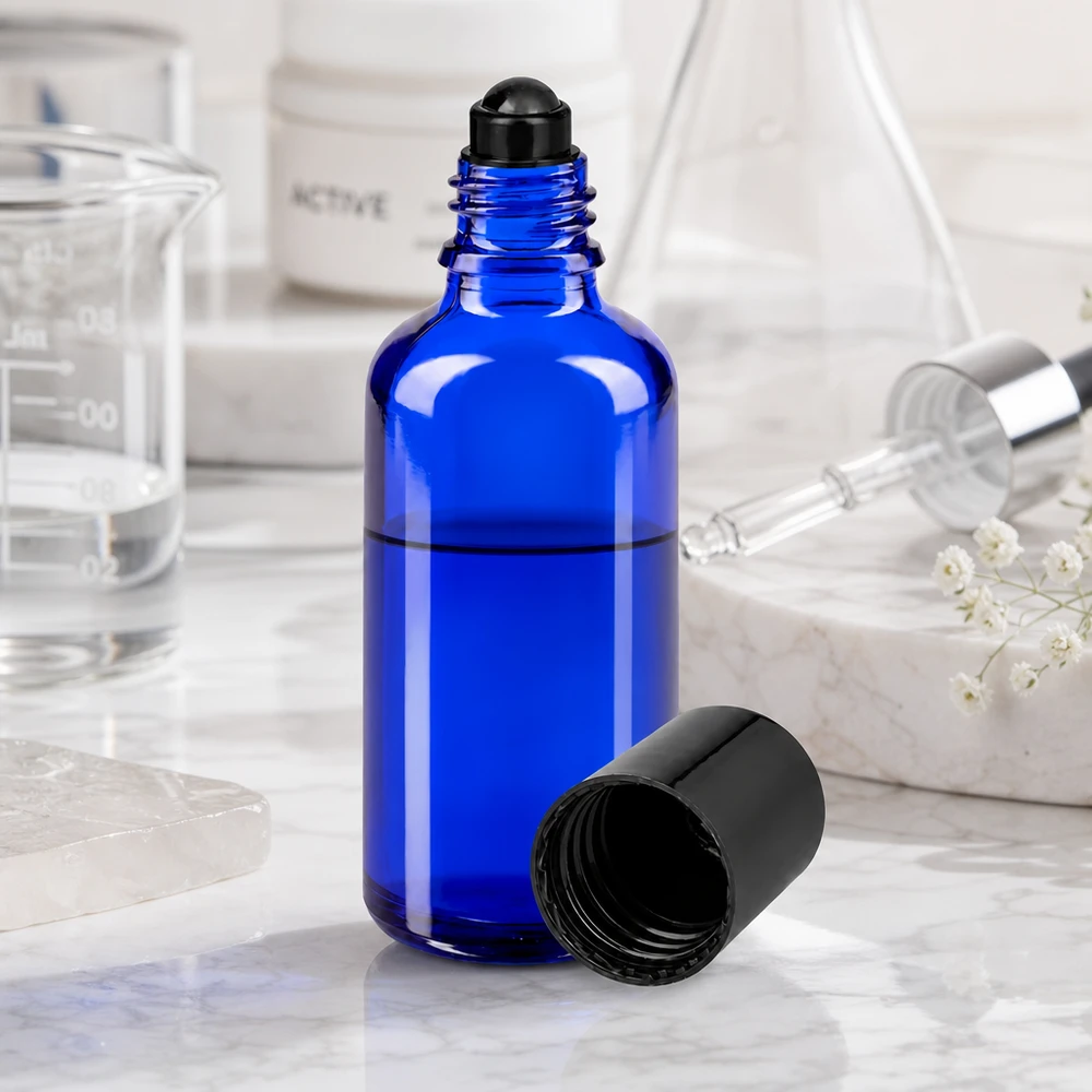 Frasco roll-on de 50 ml de color azul cobalto con tapón de rosca negro, junto a un vaso de precipitados y una pipeta