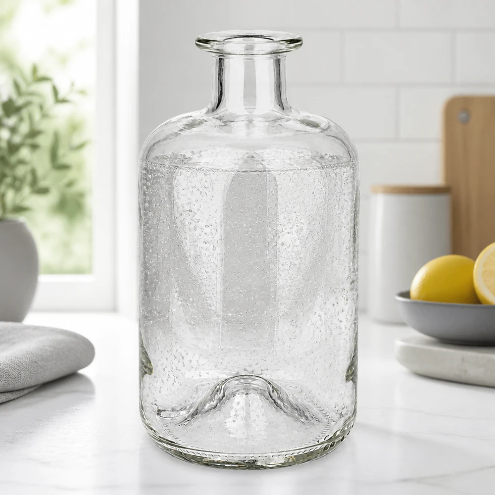 Botella de boticario Luna 500ml con textura de burbujas sobre una encimera de cocina blanca junto a limones y plantas