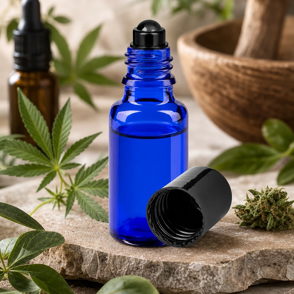 Botella de farmacia azul 20ml tapón roll-on negro Pequeño frasco roll-on de 20 ml de cristal azul de farmacia junto a una planta de cannabis y un mortero