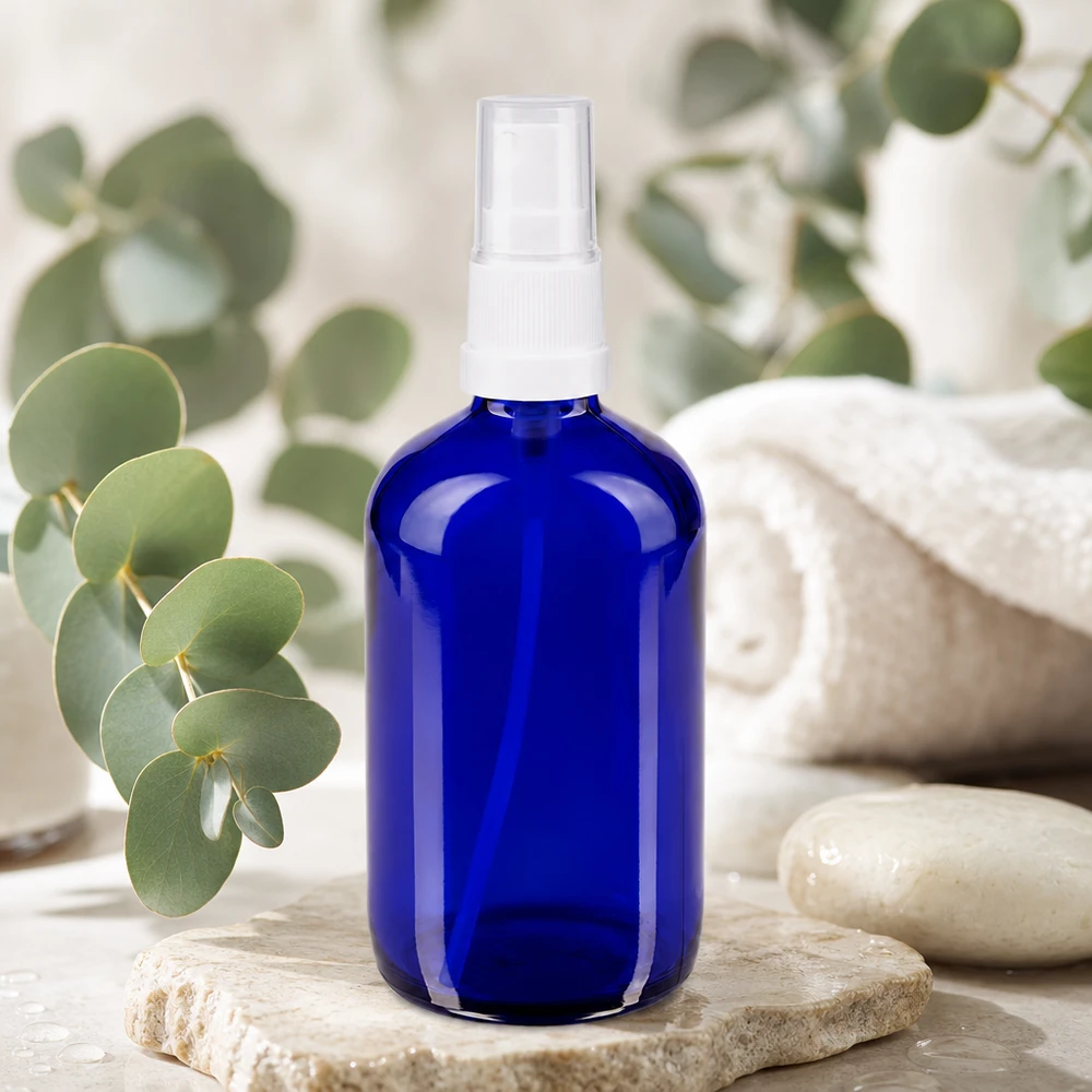Botella pulverizadora redonda de 100 ml, de cristal azul con protección UV y pulverizador blanco sobre piedra natural