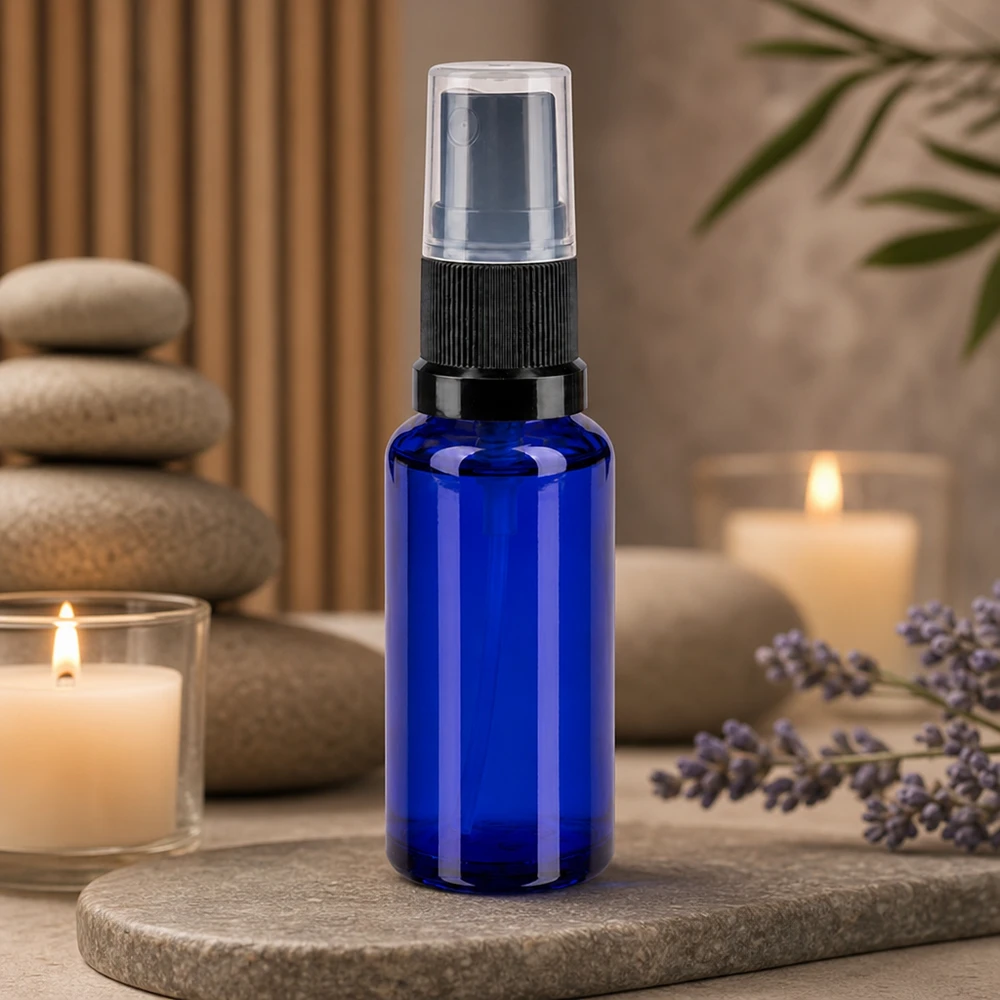 Pequeño frasco pulverizador de 30 ml, de cristal de farmacia azul cobalto con cabezal pulverizador negro sobre fondo de piedra