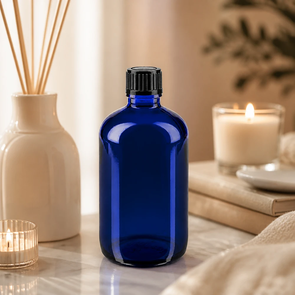Botella de farmacia azul 100ml tapón de rosca negro estándar Frasco de farmacia azul cobalto de 100 ml con tapón cuentagotas negro sobre fondo de mármol