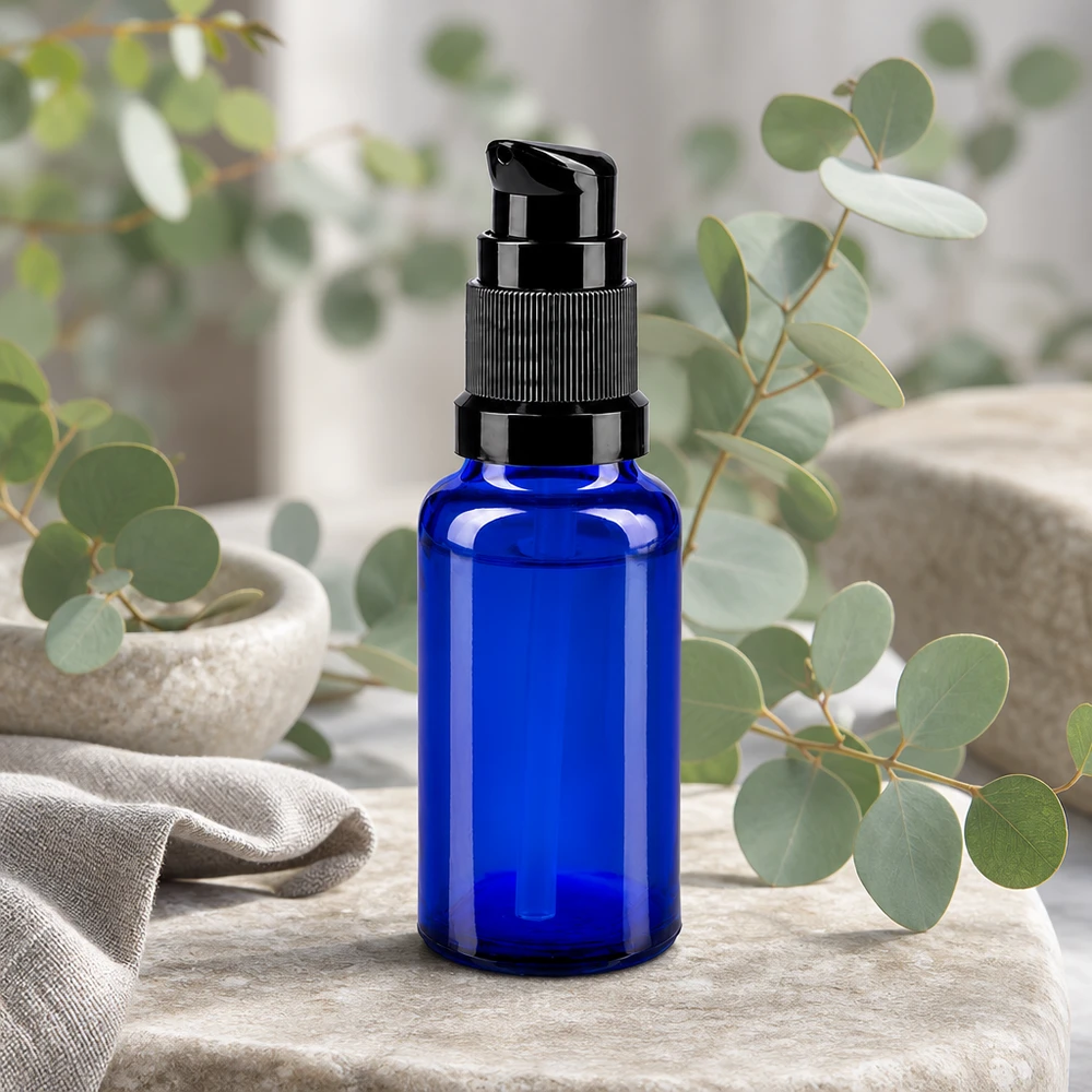 Frasco de farmacia azul de 20 ml con dosificador negro, delante de unas ramas de eucalipto