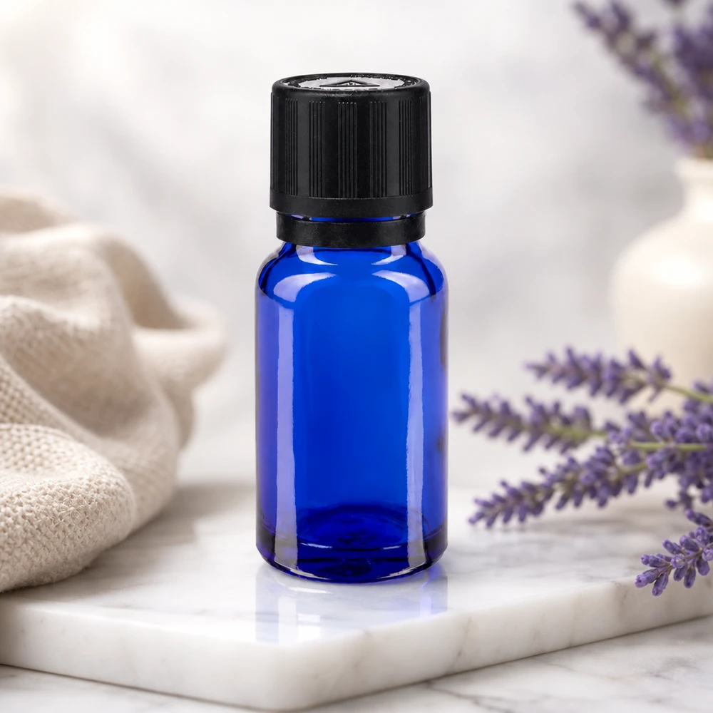Frasco cuentagotas azul de 10 ml con tapón KiSi negro junto a flores de lavanda moradas sobre una placa de mármol