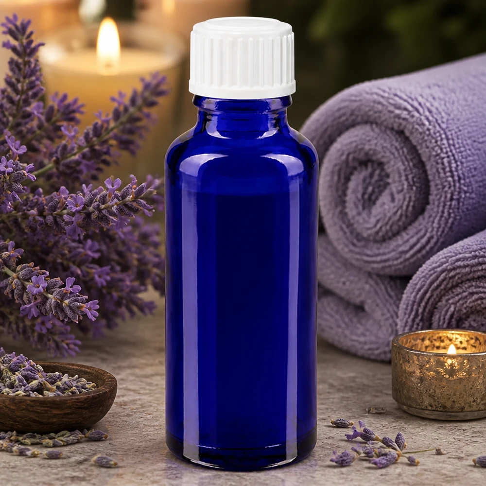 Frasco de vidrio azul de 30 ml con gotero blanco de 3 mm, rodeado de flores de lavanda y accesorios de spa