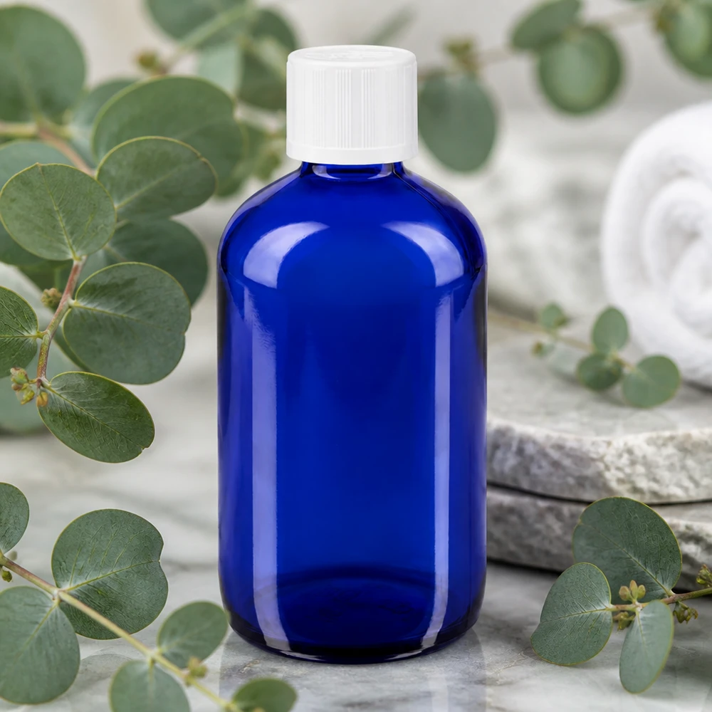 Frasco cuentagotas azul de 100 ml de cristal de farmacia con tapón blanco KiSi entre ramas de eucalipto