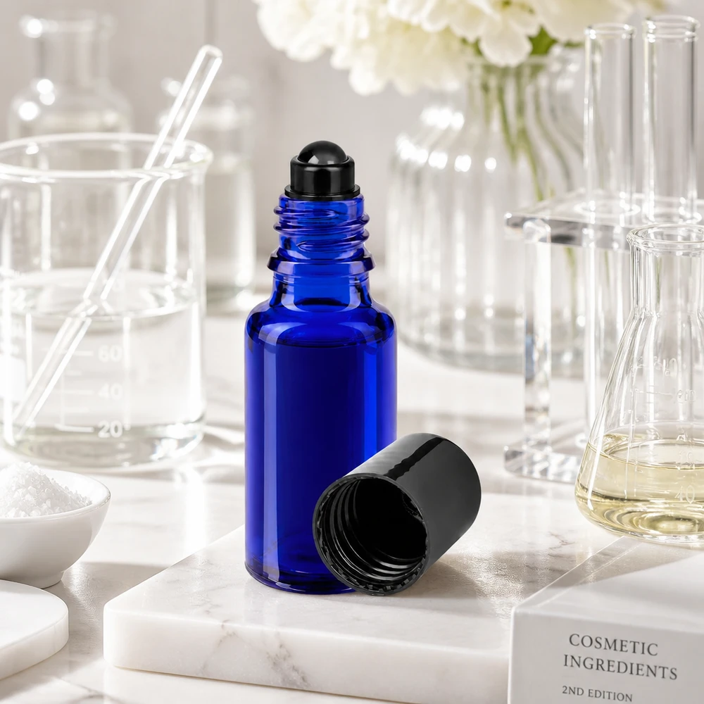 Botella de farmacia azul 20ml tapón roll-on negro Frasco roll-on abierto de 20 ml, de color azul con tapón negro, sobre una base de mármol