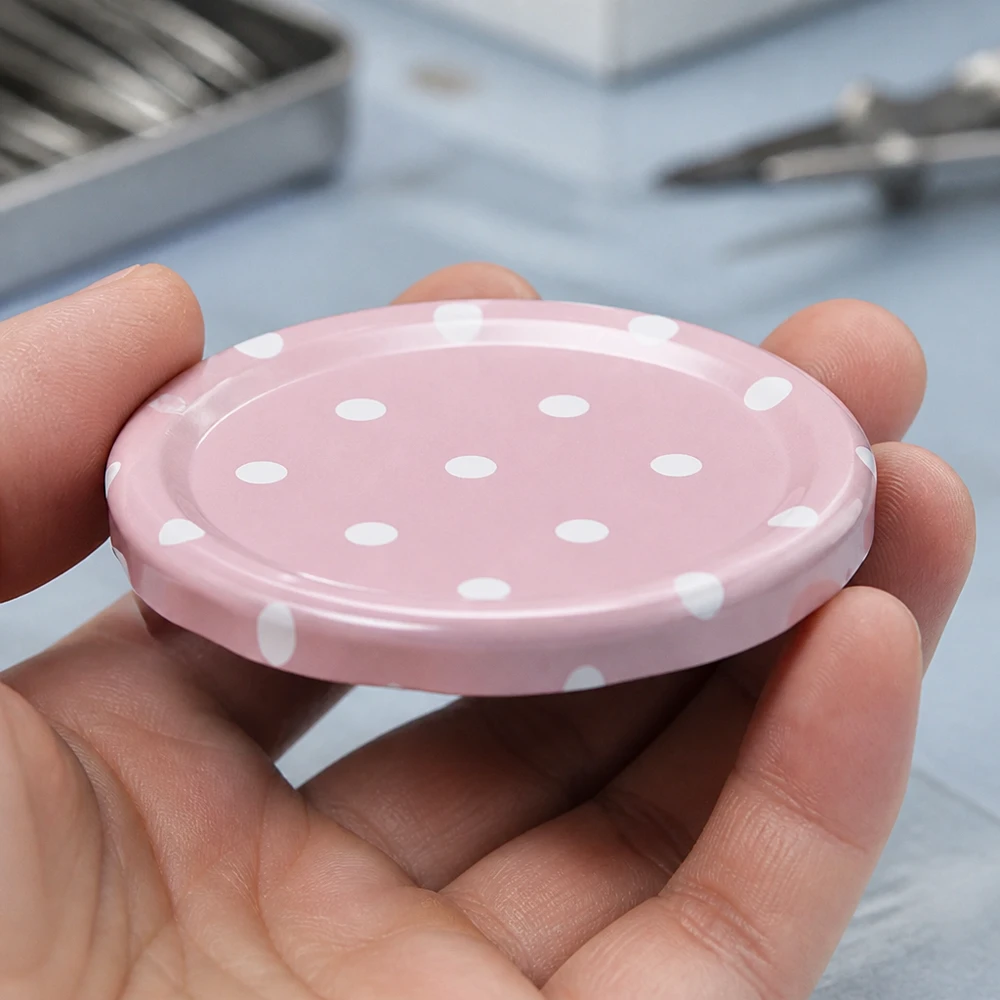 Mano sosteniendo una tapa rosa de rosca de 58 mm con puntos blancos BasicSeal TO58, vista desde arriba