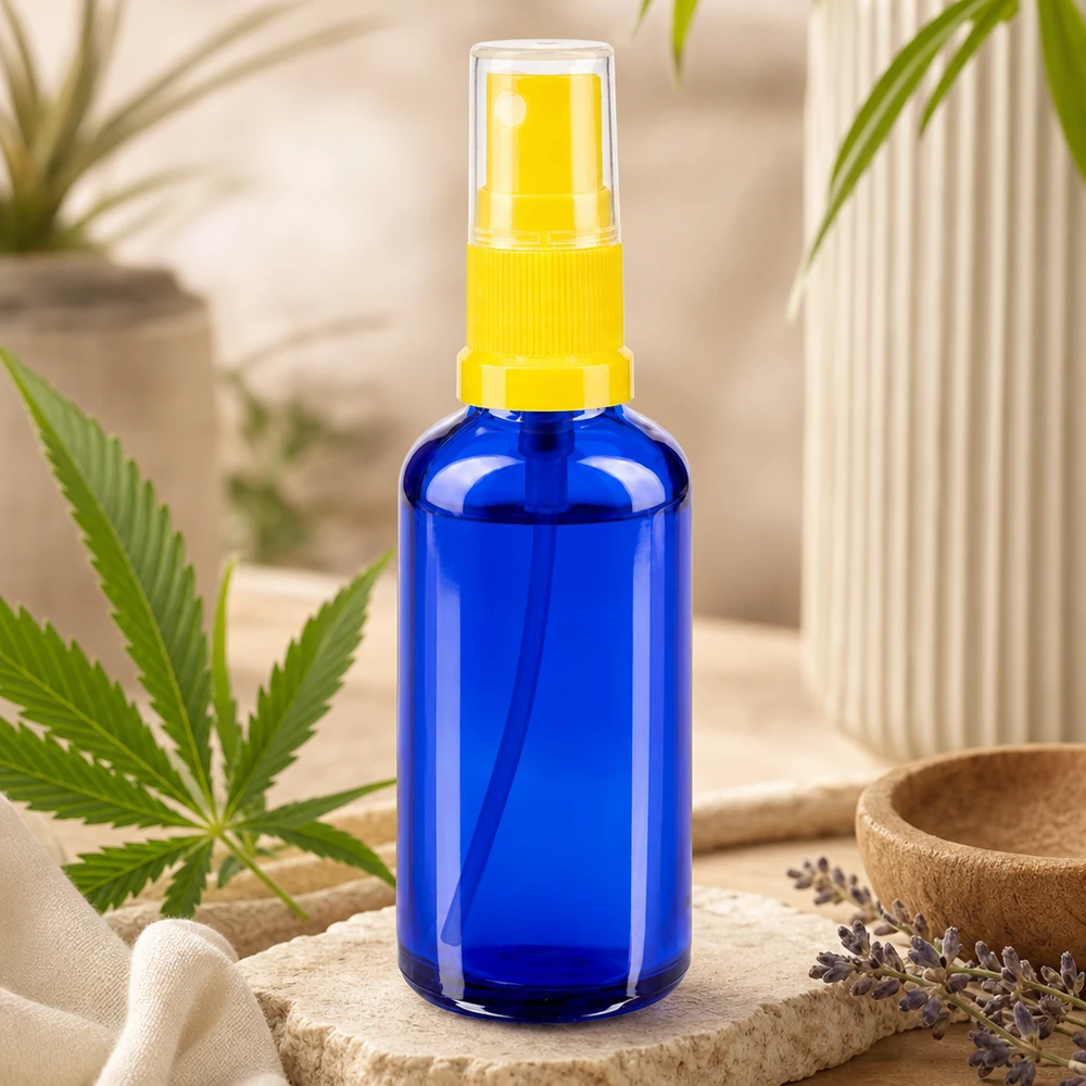 Frasco pulverizador azul de 50 ml de tipo STD, de cristal de farmacia, con pulverizador amarillo junto a una hoja de cannabis