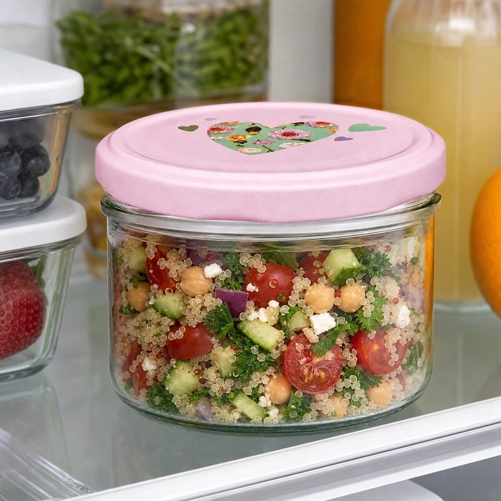 Tarro cilíndrico de 230 ml con tapa de corazón rosa lleno de ensalada de quinoa en la nevera, ideal para preparar comidas