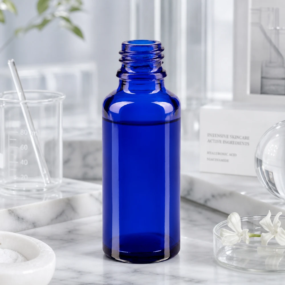 Frasco ApoGlas azul cobalto de 30 ml en un entorno de laboratorio, con vaso medidor e ingredientes para el cuidado de la piel
