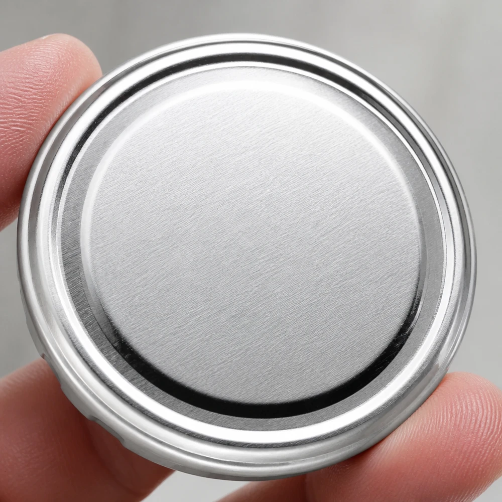 Primer plano de una tapa plateada TO82 Twist-Off de 82 mm, tapa metálica BasicSeal UNiTWIST