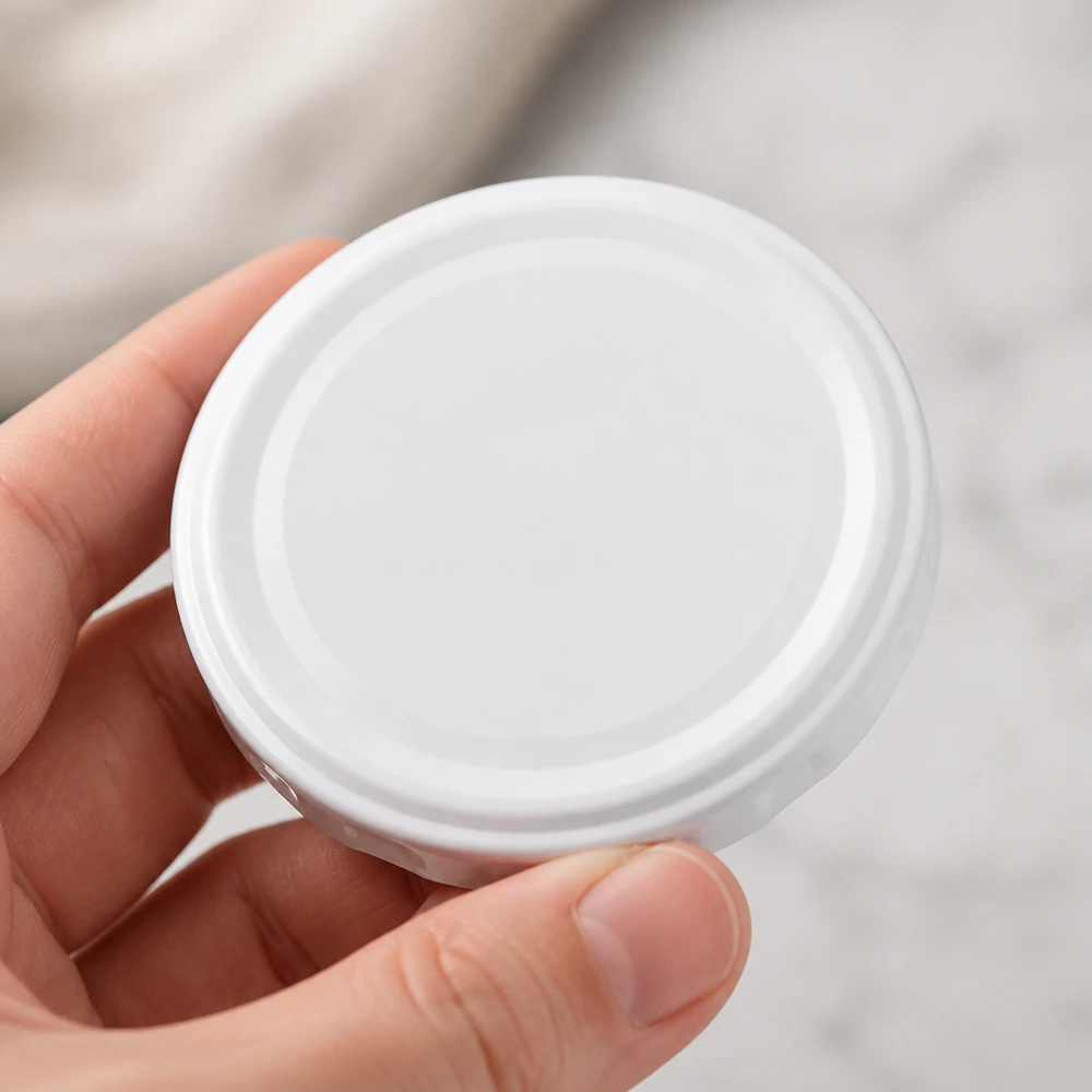Tapa BasicSeal de 58 mm, blanca (TO58deep) UNiTWIST Vista superior de la tapa blanca TO58deep de 58 mm, BasicSeal UNiTWIST, forma redonda y superficie uniforme